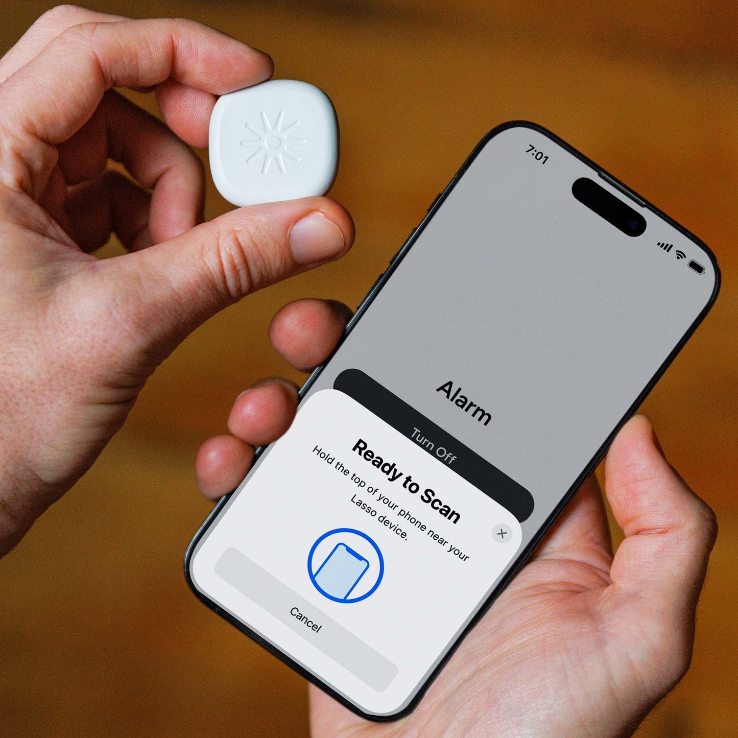 Hand holding the Lasso Alarm Clock device and iPhone displaying Lasso Alarm Clock app
