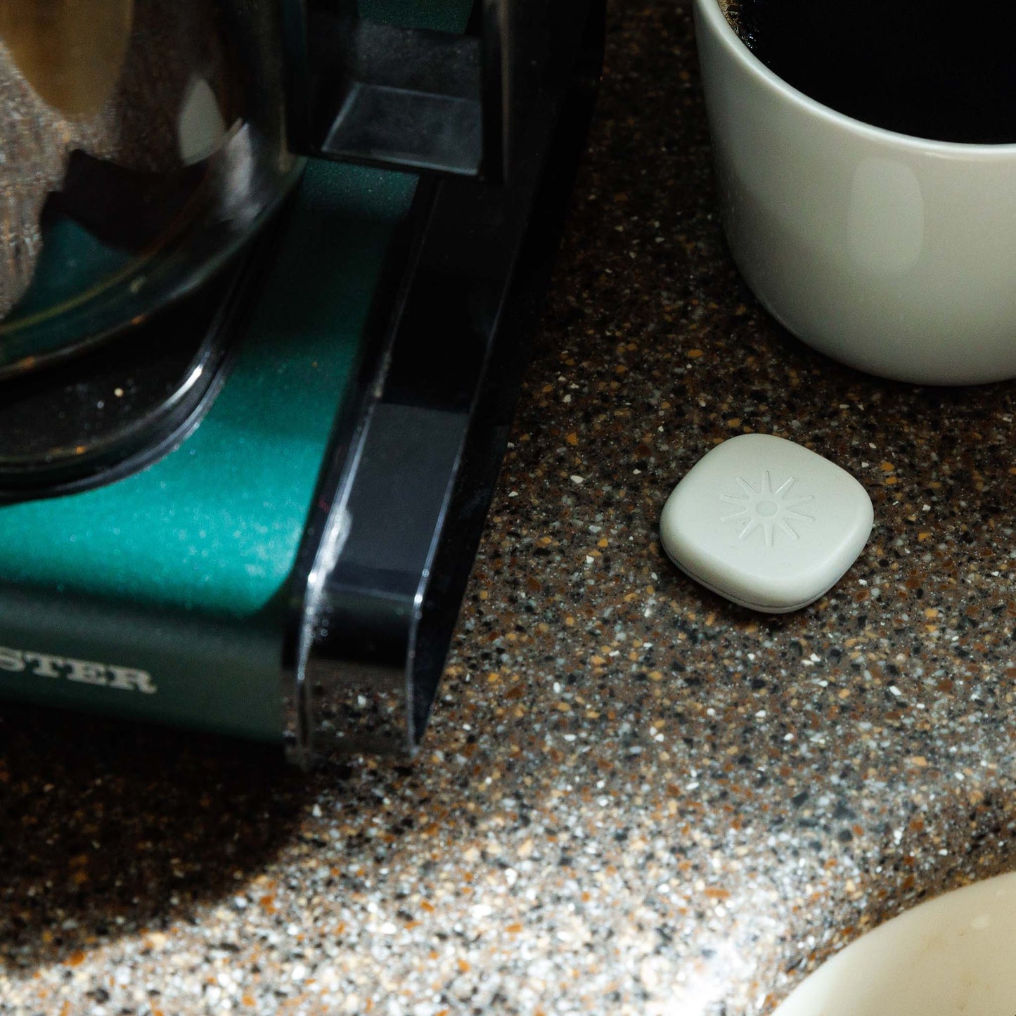 Lasso Alarm Clock device sitting next to a coffee pot